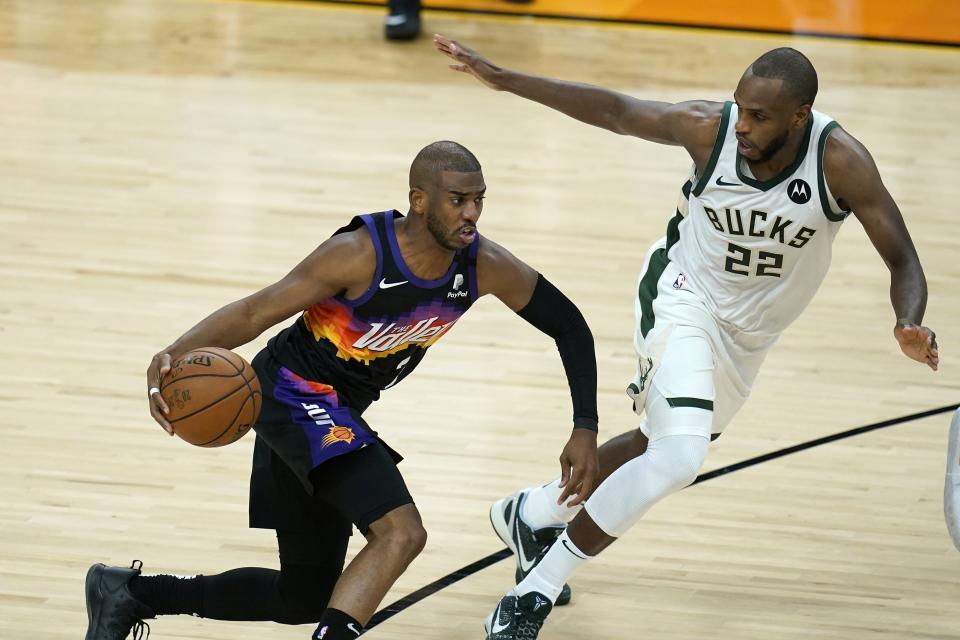 Phoenix Suns guard Chris Paul, left, dribbles the ball against Milwaukee Bucks forward Khris Middleton (22) during the second half of Game 1 of basketball's NBA Finals, Tuesday, July 6, 2021, in Phoenix. (AP Photo/Ross D. Franklin)