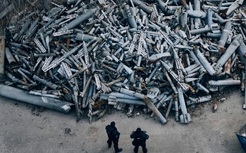 Two police officers stand in front of a huge pile of Russian rockets that hit the city of Kharkiv - Libkos/AP