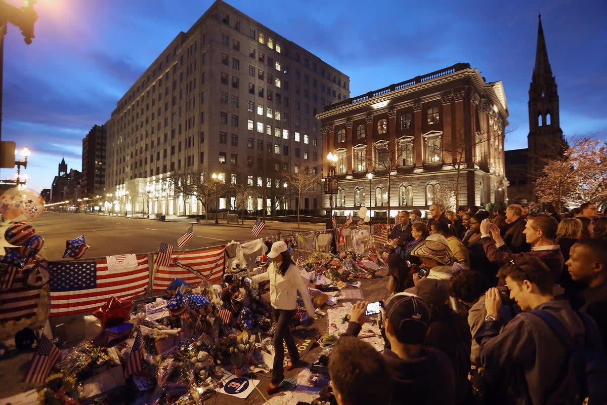 People gather at a makeshift memorial for victims near the site of the Boston Marathon bombings a day after the second suspect was captured on 20 April 2013 in Boston, Massachusetts (Mario Tama/Getty Images)