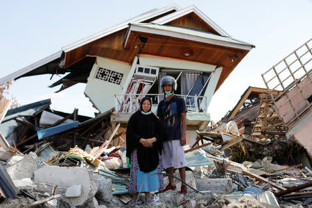 Darmi, 48, and her brother Rusli, 43, stand outside her destroyed house hit by an earthquake as they look for clothes and other belongings in the rubble, in Balaroa neighbourhood, Palu, Central Sulawesi, Indonesia, October 10, 2018. REUTERS/Jorge Silva