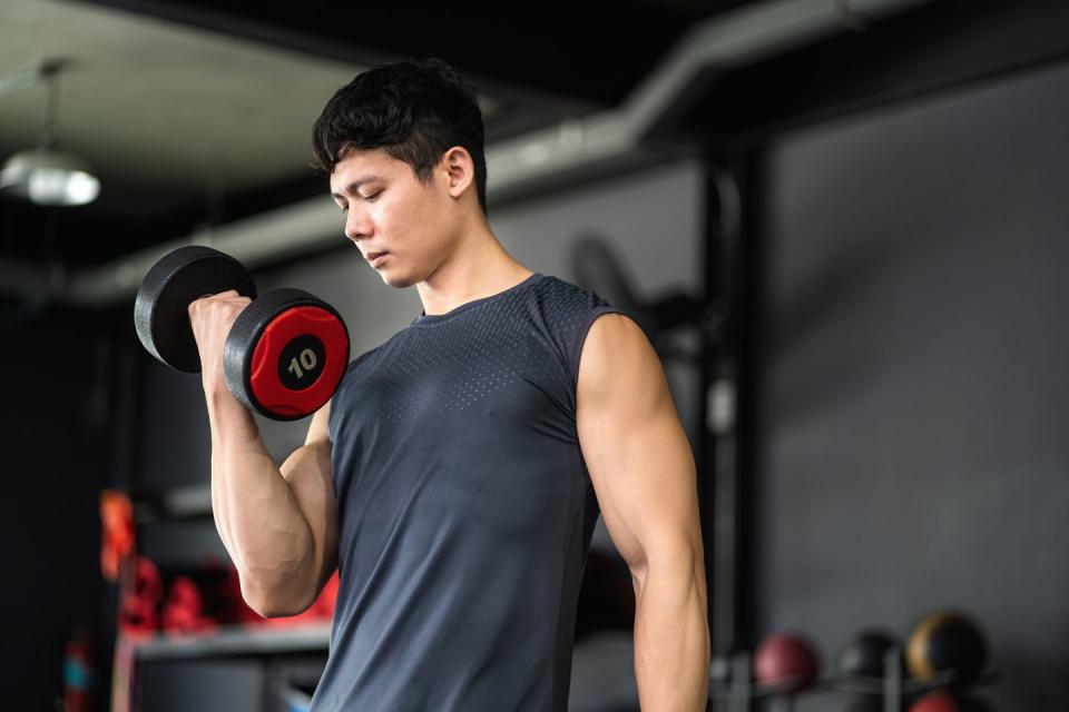 man lifting dumbbells to build arm muscles in gymconcept of exercise and health care