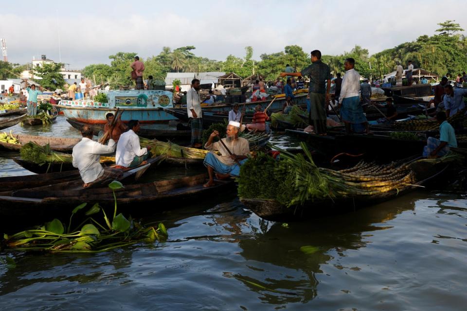 Farmers sell their vegetables, fruits and seedlings to middlemen at a biweekly floating market on the Belua river in Pirojpur (Reuters)