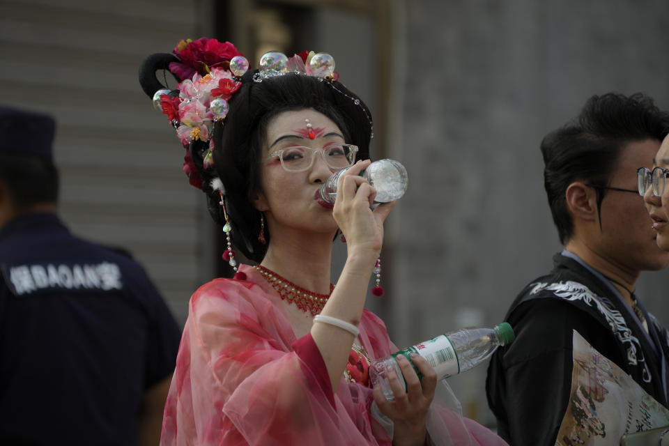 A woman wearing a traditional costume drinks water in a hot and sunny day in Beijing, Sunday, June 16, 2024. China is being buffeted by two weather extremes, with heavy rain and flooding in parts of the south and a heat wave and potential drought in the north. (AP Photo/Andy Wong)