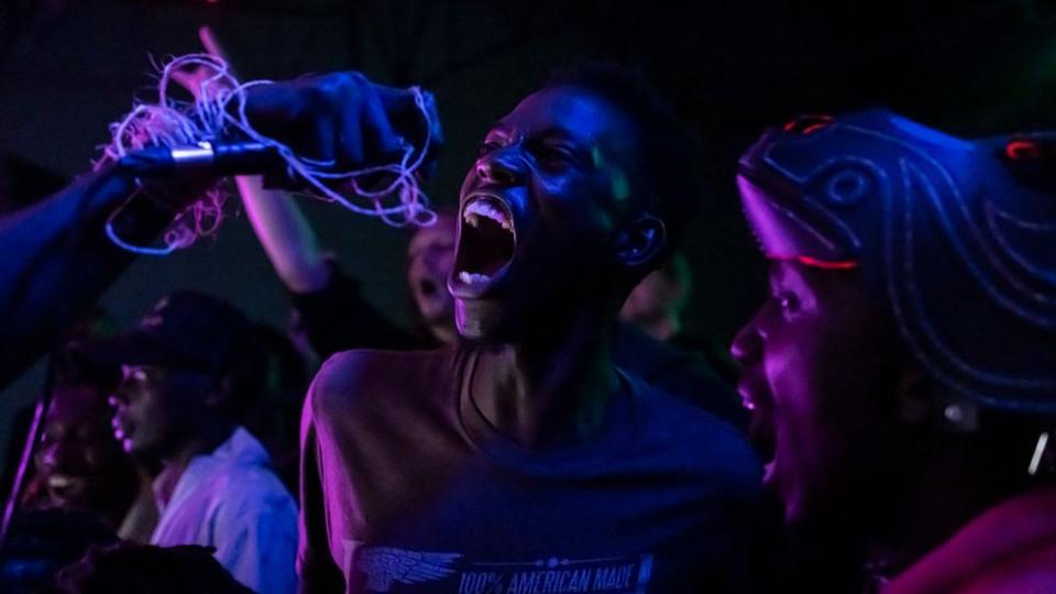 A man sings into a microphone during the performance of the black metal band Chovu at the Undertow concert held in Nairobi on March 16, 2024.