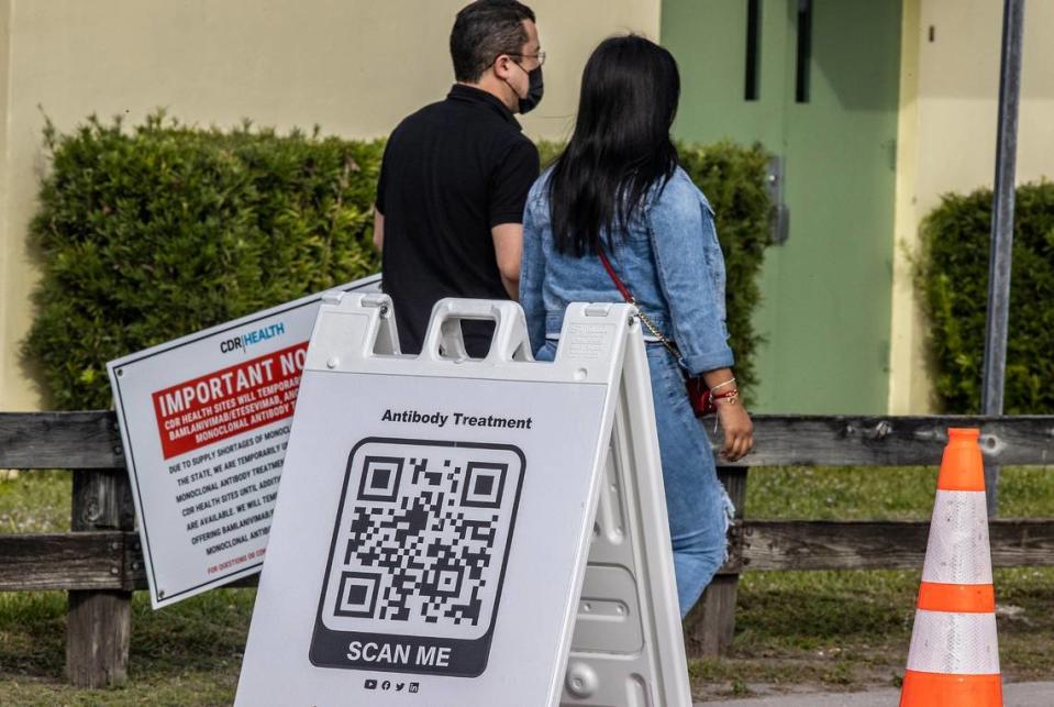 Una pareja pasa al lado de cartel con un código QR fuera de un sitio de distribución de anticuerpos monoclonales para tratar el COVID-19, en Tropical Park, el martes 4 de enero de 2021 por la tarde.