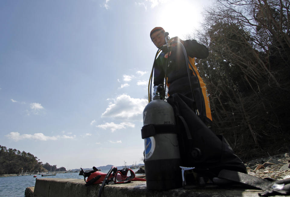 In this Sunday, March 9, 2014 photo, Yasuo Takamatsu takes off his gear after taking a diving lesson at Takenoura bay, Miyagi prefecture, northern Japan. Nearly three years after the earthquake and tsunami disaster that struck Japan's northern pacific coastline, Takamatsu is learning to scuba dive in hopes of finding his wife. As Japan marks the third anniversary of the 2011 tsunami Tuesday, 2,636 people remain missing, their bodies presumably swept out to sea. Another 15,884 have been confirmed dead. (AP Photo/Koji Ueda)