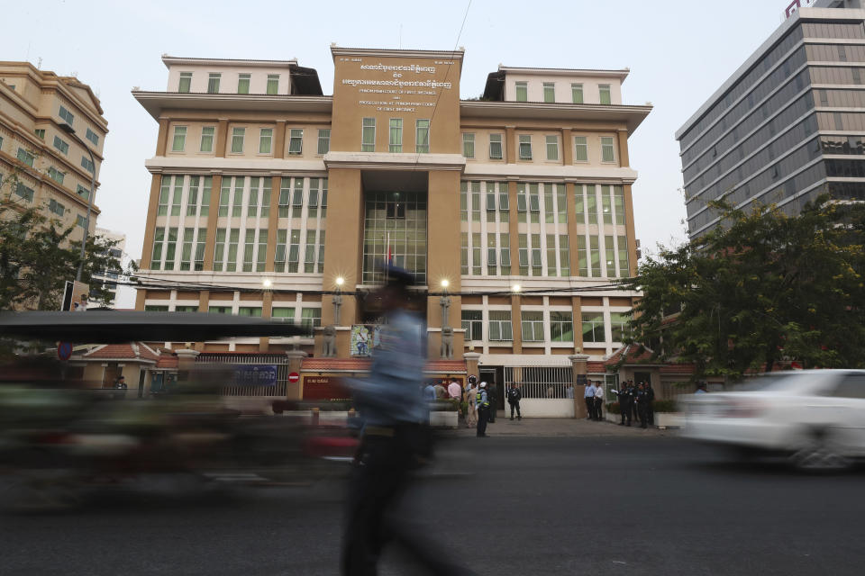 A Cambodian police officer, foreground, walks in front of the Phnom Penh Municipal Court before hearing of Kem Sokha, the head of the dissolved Cambodia National Rescue Party, in Phnom Penh, Cambodia. The trial of the top Cambodian opposition leader charged with treason began Wednesday, more than two years after he was arrested in what is widely seen as a politically motivated prosecution. (AP Photo/Heng Sinith)