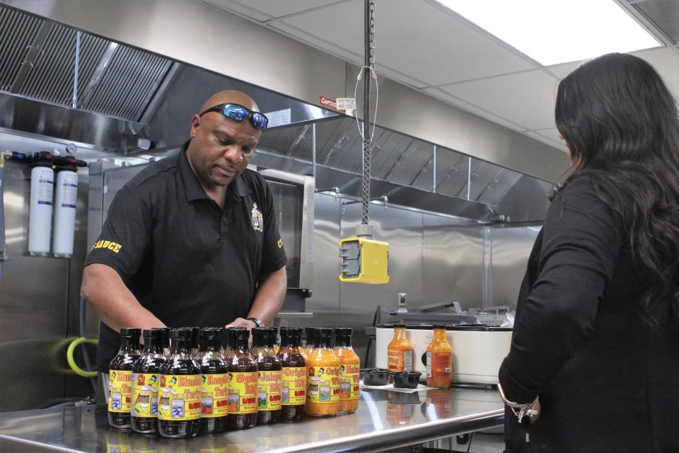 Calvin McElroy, a small business owner who owns C's Sauce, sells some of his product to a customer during the grand opening of Fuel Kitchens on Friday, March 1, 2024.