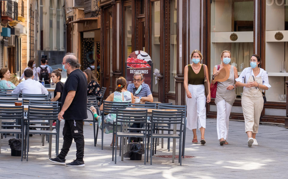 SEVILLA, SPAIN - JULY 15: Three women are seen walking with a hand fun and others are sitting at a coffe shop on the first day of mandatory use of masks in Seville on July 15, 2020 in Madrid, Spain. (Photo by Eduardo Briones/Europa Press via Getty Images)