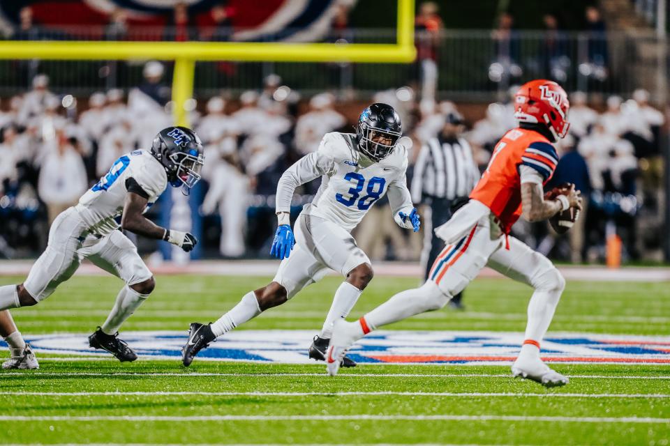 Liberty quarterback Kaidon Salter (7) looks downfield under pressure from MTSU’s Zabrien Harden (38) during the Blue Raiders' CUSA game at Liberty Tuesday.