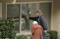 Dorothy Campbell and her son, Charlie Campbell, talk through a window with her husband, Gene Campbell, at the Life Care Center of Kirkland, the long-term care facility linked to several confirmed coronavirus cases in the state, in Kirkland