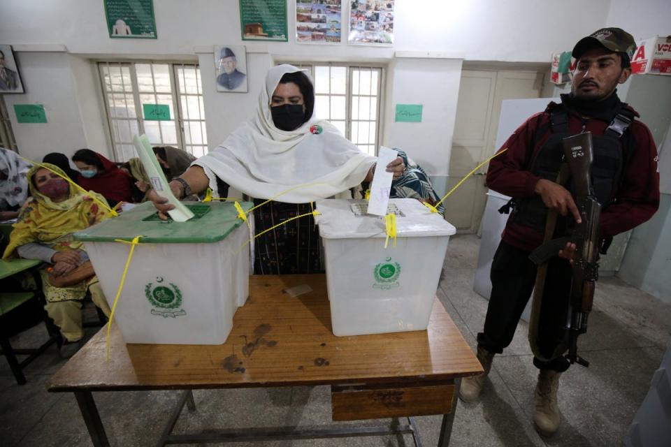 A policeman stands guard as a woman cast their ballot at a polling station during general elections in Peshawar (EPA)