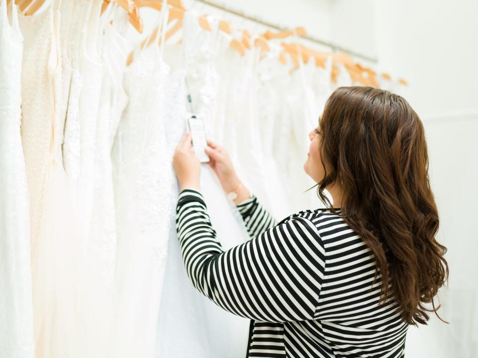 A woman looks at the price tag of a wedding dress.