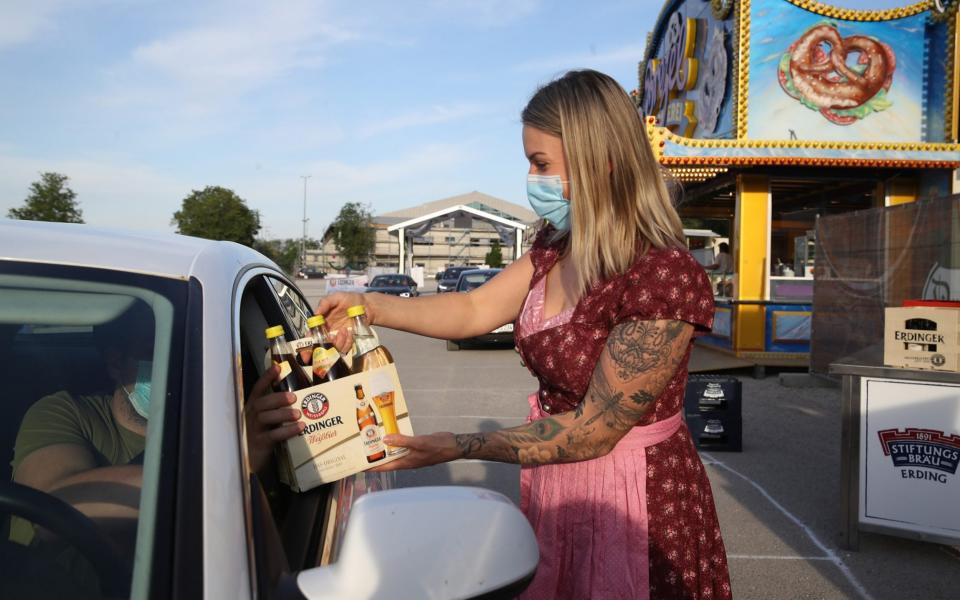 Woman serves beer to customer through car window - GETTY IMAGES