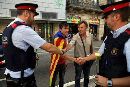 Gaudi Vall and his son Gaudi shake hands with Catalan Mossos d'Esquadra officers after giving them carnations during a gathering in support of the banned October 1st independence referendum in Barcelona, Spain, September 24, 2017. REUTERS/Susana Vera