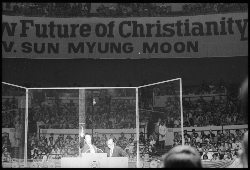 Reverend Sun Myung Moon gestures emphatically on the stage of Madison Square Garden during rally attended by overflow crowd. His supporters gave away free tickets in excess of the Garden capacity and demonstrators picketed his support of the South Korean President in a crush of people and causes in the street.