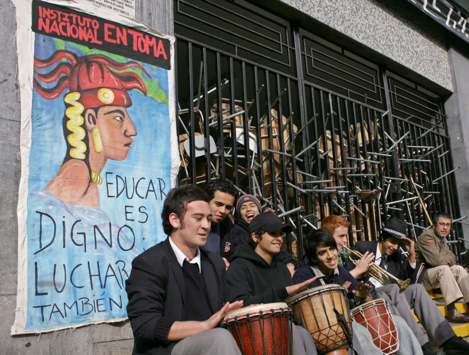 ARCHIVO - En esta imagen del 31 de mayo de 2006, estudiantes de secundaria tocan música ante el Instituto Nacional, que bloquearon con sillas y mesas en Santiago de Chile. El cartel dice "Educar es digno, luchas también". (AP Foto/Santiago Llanquin)