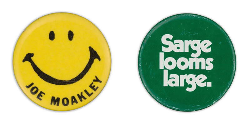 A yellow smiley face with Joe Moakley's name under the mouth, and a green button with bold font reading "Sarge looms large."