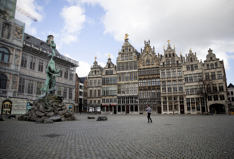 A woman runs though the nearly empty historic center of Antwerp, Belgium, Saturday, March 14, 2020. Belgium has closed schools, restaurants and bars, as as well as cancelled sporting and cultural events in an effort to contain the spread of the coronavirus. For most people, the new coronavirus causes only mild or moderate symptoms, such as fever and cough. For some, especially older adults and people with existing health problems, it can cause more severe illness, including pneumonia. (AP Photo/Virginia Mayo)