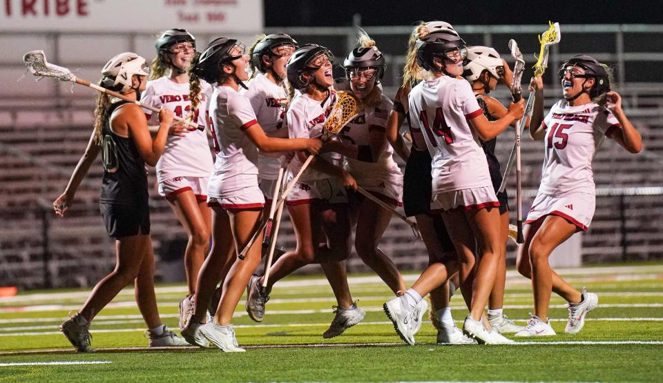 Vero Beach's Savina Magaro (center) is mobbed by her teammates after netting the winning goal in overtime to send Vero Beach to a 12-11 victory over Viera in a Region 2-2A girls lacrosse semifinal Tuesday, April 30, 2024, at Vero Beach high School.