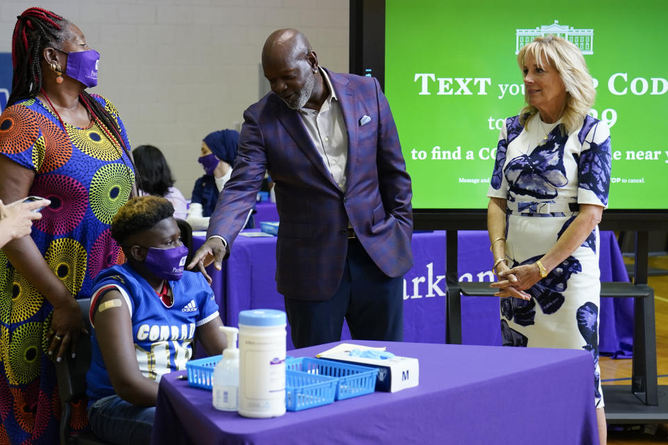Former Dallas Cowboy and Football Hall of Famer Emmitt Smith talks with a COVID-19 vaccine recipient during a tour of vaccination site at Emmett J. Conrad High School in Dallas, Tuesday, June 29, 2021. First lady Jill Biden looks on at right. (AP Photo/Carolyn Kaster, Pool)
