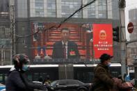 A giant screen shows Chinese President Xi Jinping attending the opening session of the National People's Congress (NPC) at the Great Hall of the People, in Beijing