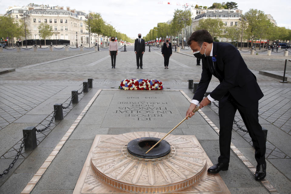 French President Emmanuel Macron lights up the flame at the Tomb of the Unknown soldier during a ceremony at the Arc de Triomphe to mark the 76th anniversary of the end of World War II, in Paris, Saturday, May 8, 2021.(Christian Hartmann/Pool via AP)