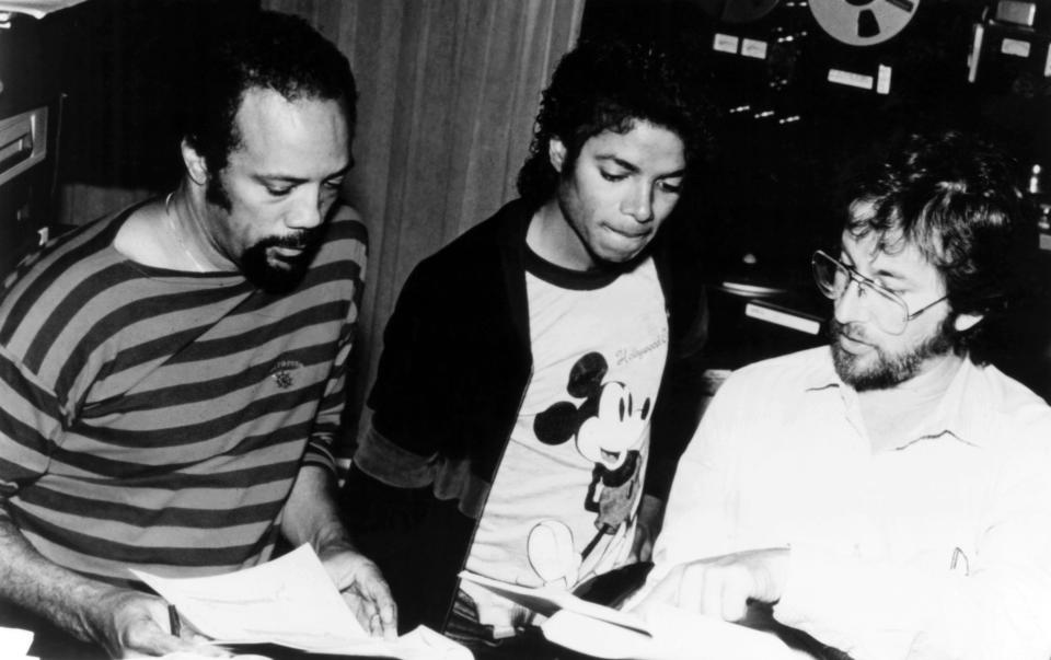 Quincy Jones, Michael Jackson, and George Martin reviewing sheet music together in a studio in the 1980s