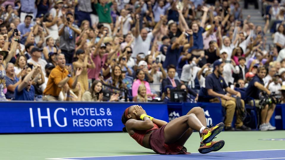 coco gauff falling to the court on her back as fans cheer in the background