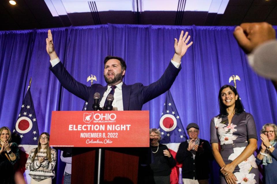 JD Vance celebrates his election victory with his hands in the air as Usha Vance looks on.