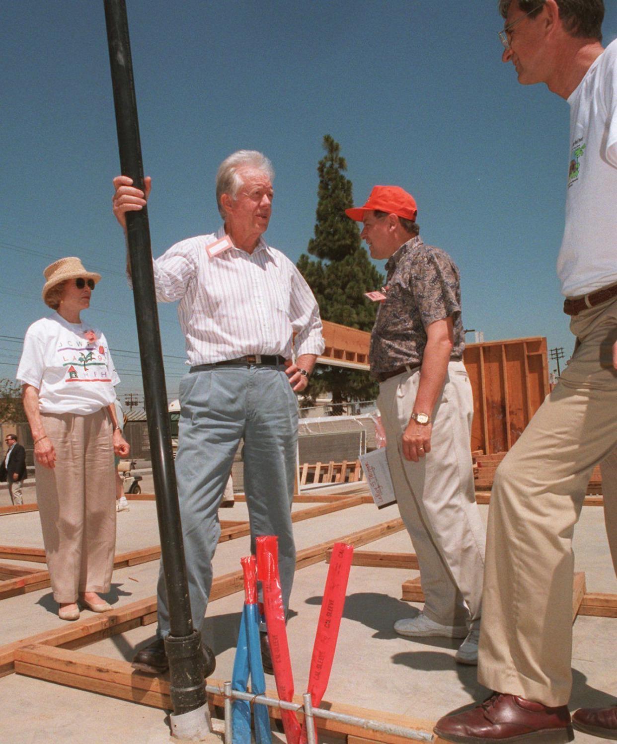 Former President Jimmy Carter, left center; and his wife Roselynn, left; listen as Millard Fuller, right; president and founder of Habitat for Humanity; and Leroy Troyer discuss the layout of a house on June 18, 1995, which will be built on the foundation they are standing on in a remarkable six days, in an unreported location. The former president has been a volunteer for Habitat for Humanity since 1984.