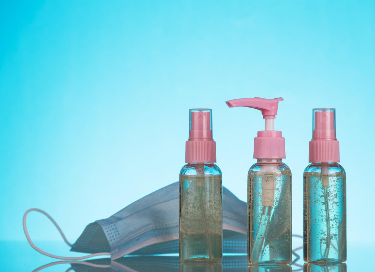 Sanitizers in various jars and a medical mask on a blue background