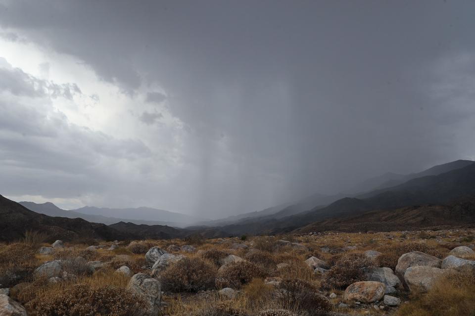 Rain pours in the distance over the Indian Canyons in the Agua Caliente Indian Reservation south of Palm Springs, Calif., June 22, 2022. 