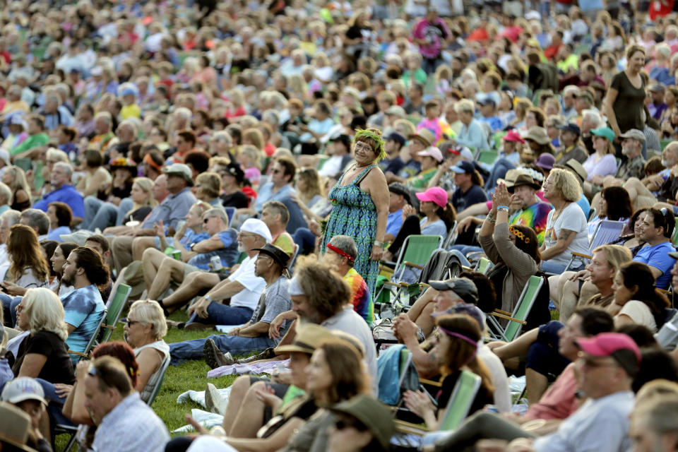 FILE - Music fans listen to the band Blood, Sweat and Tears play at a concert celebrating the 50th anniversary of Woodstock in Bethel, N.Y., Aug. 16, 2019. An estimated 450,000 people attended the Woodstock festival in August 1969, and most of that crowd was composed of teenagers or young adults now in the twilight of their lives. That ticking clock is why the Museum at Bethel Woods, based at the site of the festival, is immersed in a five-year project traveling around the United States recording the oral histories of people were there, preserving the Woodstock memories before they fade away. (AP Photo/Seth Wenig, File)