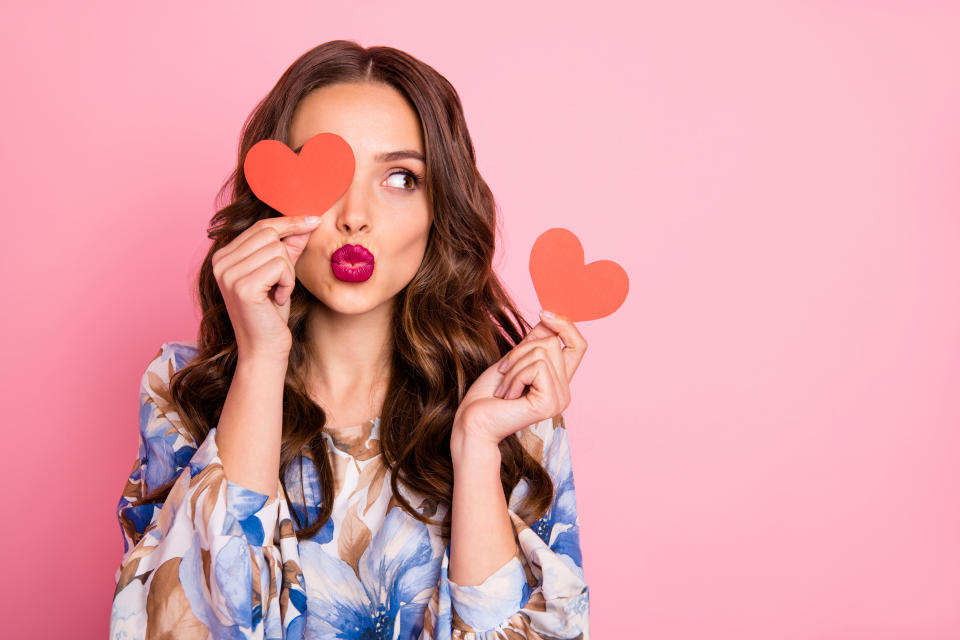 Close-up portrait of her she, nice-looking attractive lovely coquettish cheerful cheery wavy-haired girl holding in hands two small little heart sending you kiss isolated over pink pastel background