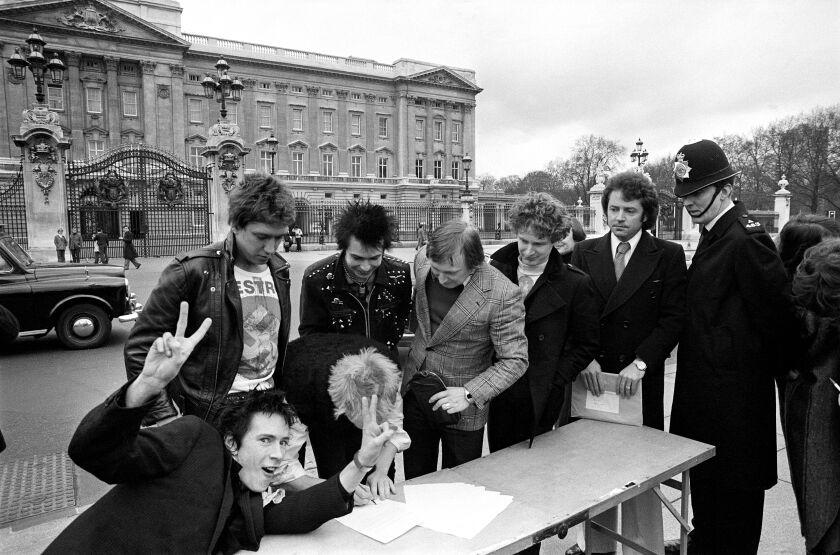 The Sex Pistols sign a copy of their new recording contract with A & M Records outside Buckingham Palace in 1977.