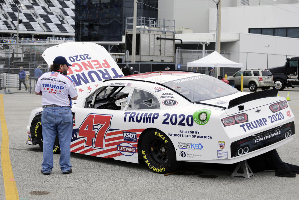 Crew members make adjustments to Joe Nemecheck's car sponsored by Patriots PAC of America during practice for the NASCAR Xfinity Series auto race at Daytona International Speedway, Friday, Feb. 14, 2020, in Daytona Beach, Fla. Trump is scheduled to be present for the Daytona 500 on Sunday and he will find this environment as welcoming as one of his campaign rallies. (AP Photo/Terry Renna)