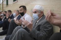 Bosnian Muslims, wearing face masks to protect themselves from the COVID-19 infection, attend Eid al-Fitr prayers in Konjic, Bosnia, Thursday, May 13, 2021. Muslims celebrated Eid al-Fitr in a subdued mood for a second year as the COVID-19 pandemic again forced mosque closings and family separations on the holiday marking the end of Ramadan. (AP Photo/Kemal Softic)