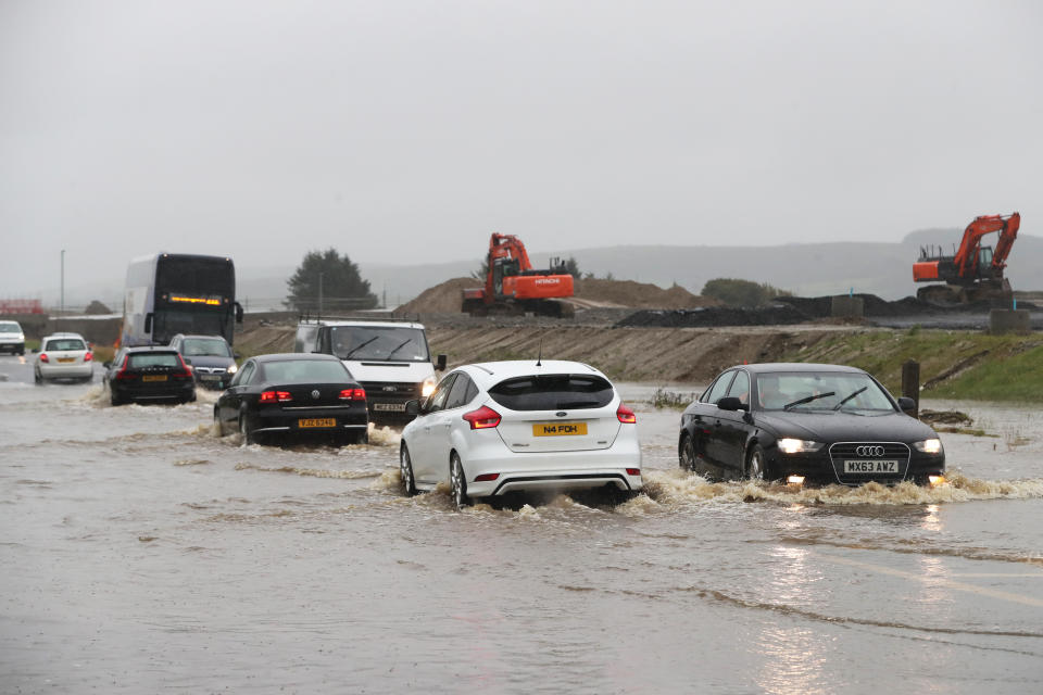 Cars make their way through a flooded road in Claudy, County Londonderry. The UK's wet weekend will continue as a weather warning for rain across parts of Wales and England has been extended.