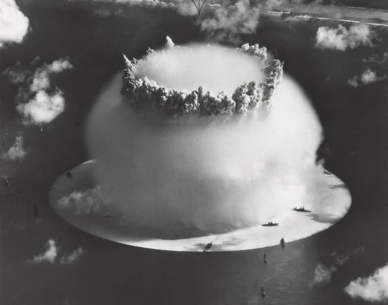 Crossroads Baker, showing the white surface "crack" under the ships, and the top of the hollow spray column protruding through the hemispherical Wilson cloud. Bikini Island beach in the background. A 21 kiloton underwater nuclear weapons effects test, known as Operation CROSSROADS (Event Baker), conducted at Bikini Atoll (1946). Image courtesy of US Govt. Defense Threat Reduction Agency.