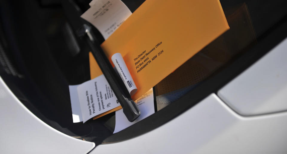 Parking ticket tucked under a car's windscreen wiper.