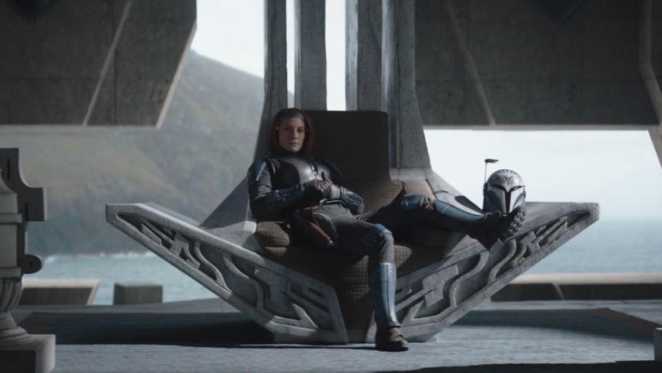 Bo-Katan sits in her castle's throne with her leg draped over the arm on The Mandalorian