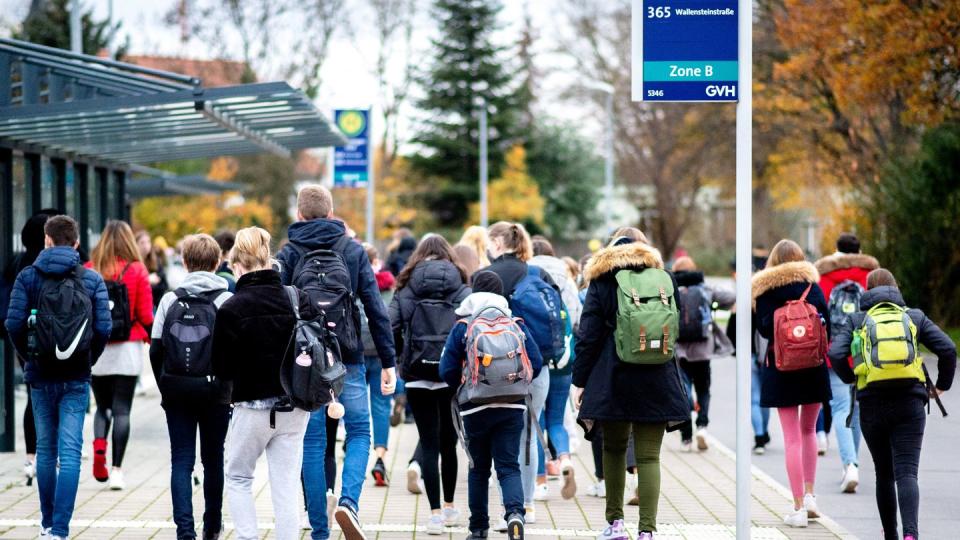 Schülerinnen und Schüler gehen mit ihren Schulrucksäcken von einer Bushaltestelle zu ihrer Schule in Niedersachsen.