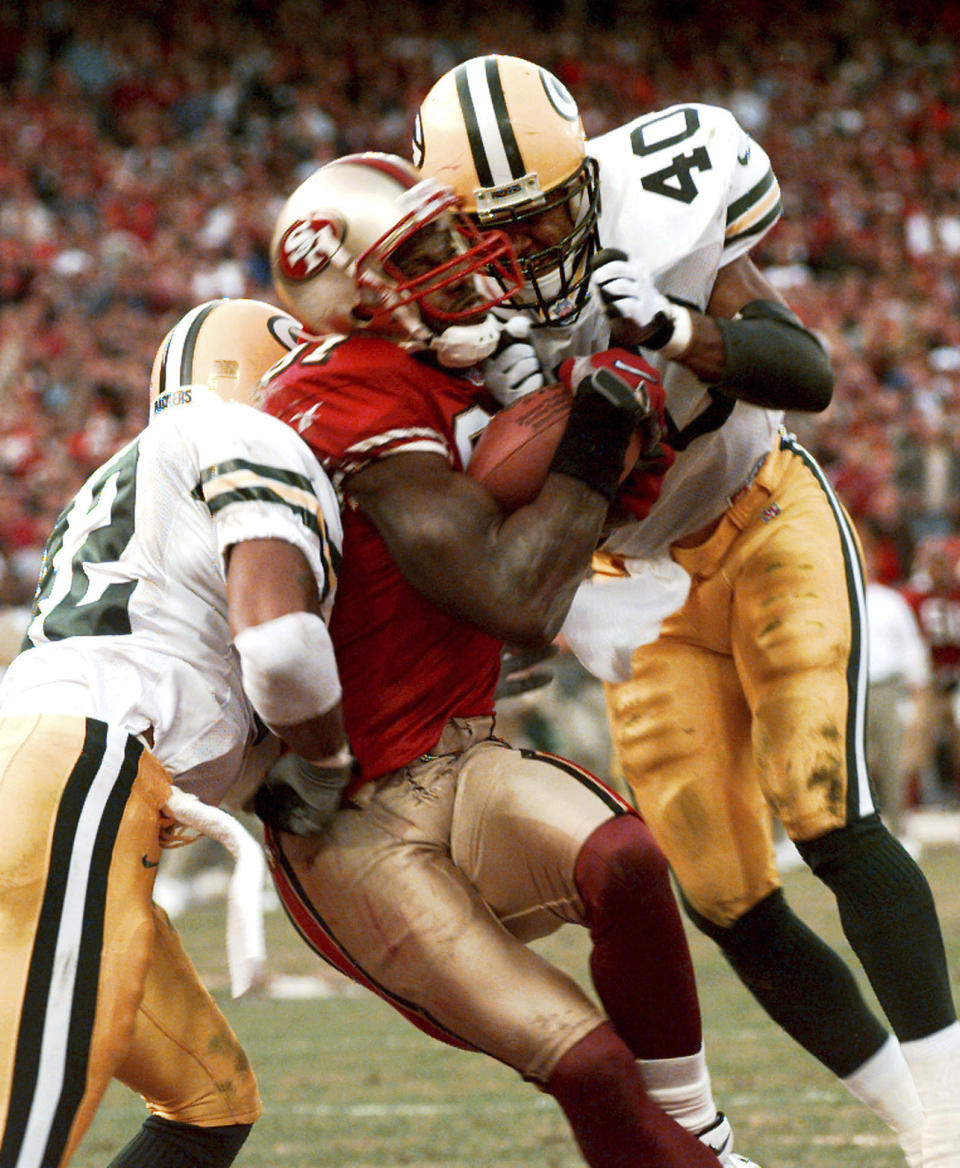 FILE - San Francisco 49ers' wide receiver Terrell Owens pulls in a 25-yard touchdown pass from quarterback Steve Young as Green Bay Packers' safeties Pat Terrell (40) and Darren Sharper defend late in the fourth quarter of the NFC wild card playoff game at 3COM Park in San Francisco, Sunday, Jan. 3, 1999. With 8 seconds left and the Niners trailing by four, Young stumbled dropping back from center and then threaded a 25-yard pass between a phalanx of Packers to Owens. (AP Photo/Susan Ragan, File)