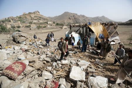 People gather around the wreckage of a house destroyed by an air strike in the Bait Rejal village, west of Yemen's capital Sanaa April 7, 2015. REUTERS/Khaled Abdullah