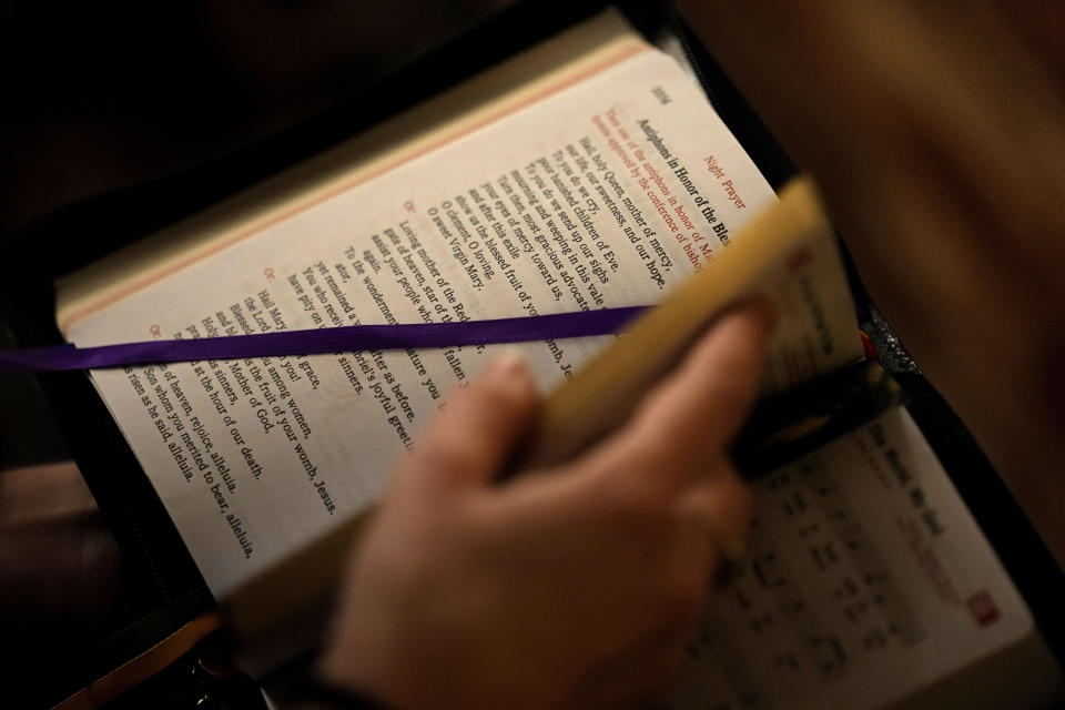 Benedictine College student Niki Wood looks through her prayer book before evening prayers with her roommates in the house they share Sunday, Dec. 3, 2023, in Atchison, Kan. In a deeply secular America, where an ever-churning culture provides few absolute answers, Benedictine offers the reassurance of clarity. (AP Photo/Charlie Riedel)