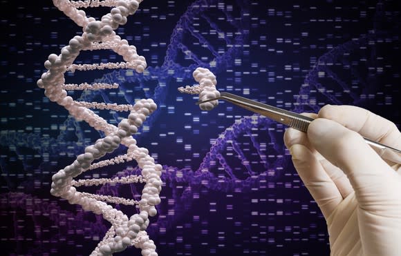 A gloved hand removing a section from a DNA molecule.