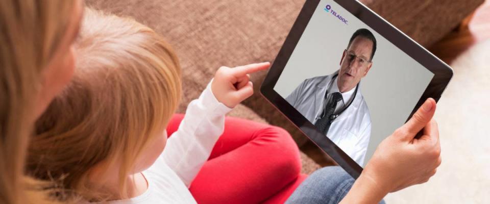 An adult and child using a tablet for a Teladoc video visit with a doctor