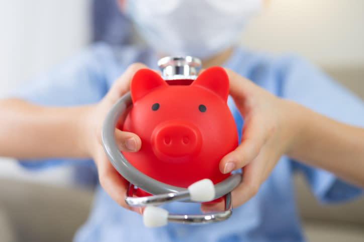 A kid holding a piggy bank wrapped in a stethoscope