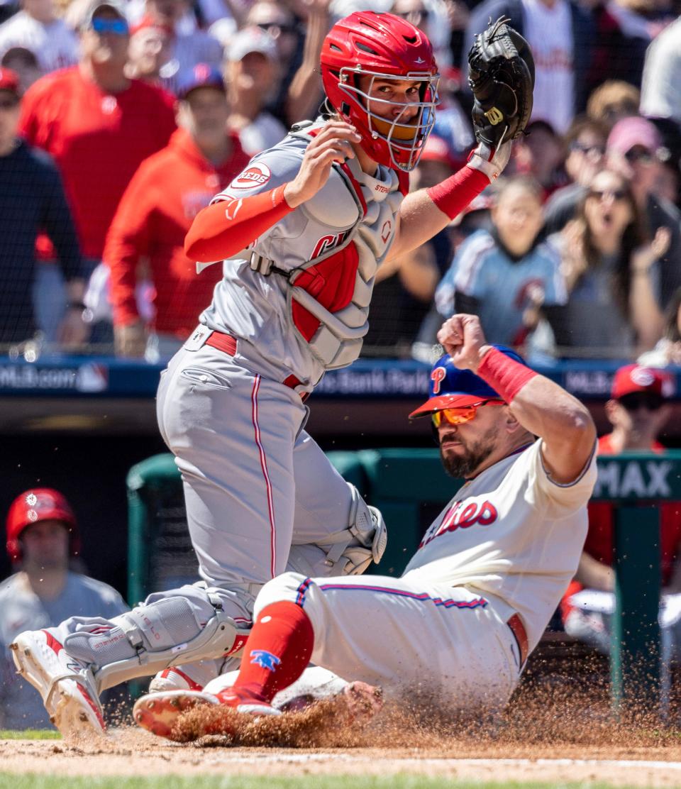 Philadelphia Phillies' Kyle Schwarber scores on an RBI by Nick Castellanos before Cincinnati Reds catcher Tyler Stephenson can make the tag during the first inning of a baseball game, Sunday, April 9, 2023, in Philadelphia.